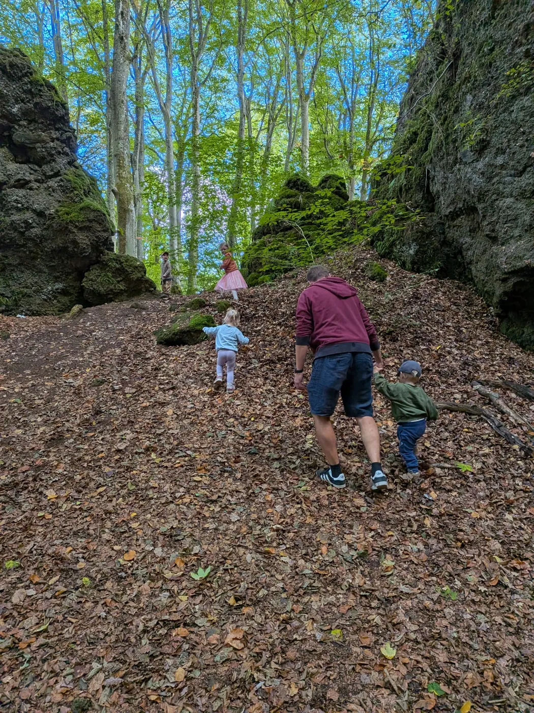 Erwachsener und Kinder wandern gemeinsam durch den Herbstwald