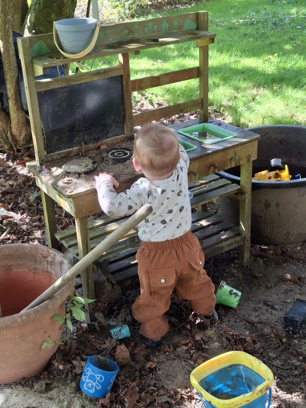Kleinkind spielt an einer Matschküche im Garten