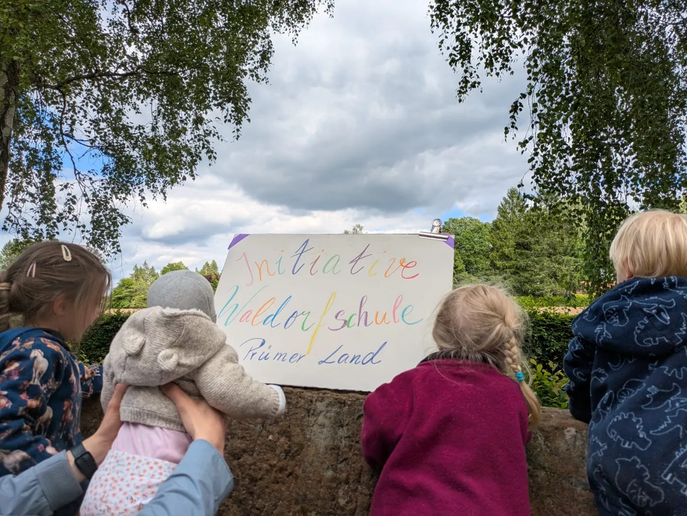 Kinder von hinten mit dem Schild der Initiative Waldorfschule Prümer Land